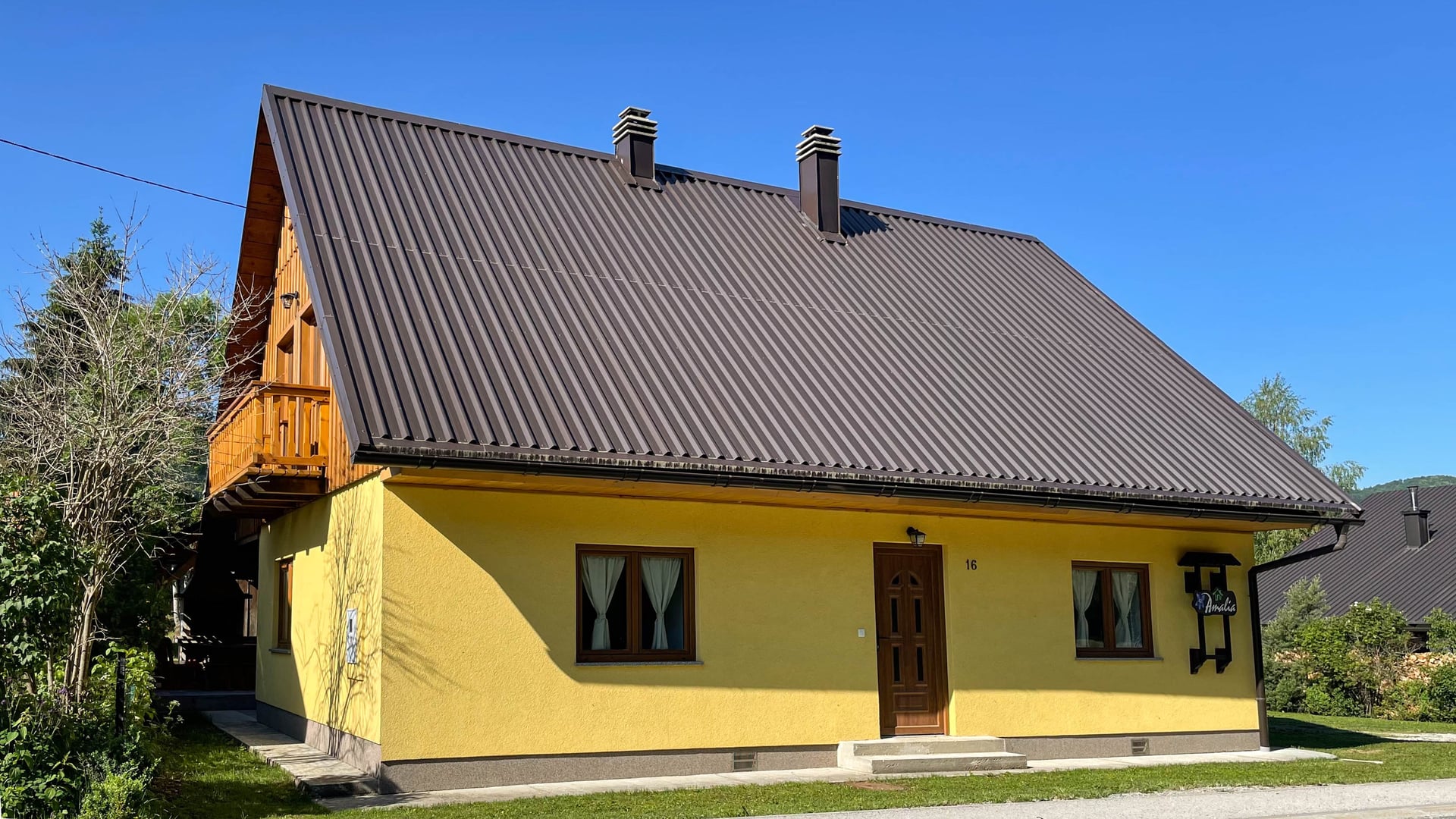 Vila Demo – žuta fasada kuće na sunčan dan